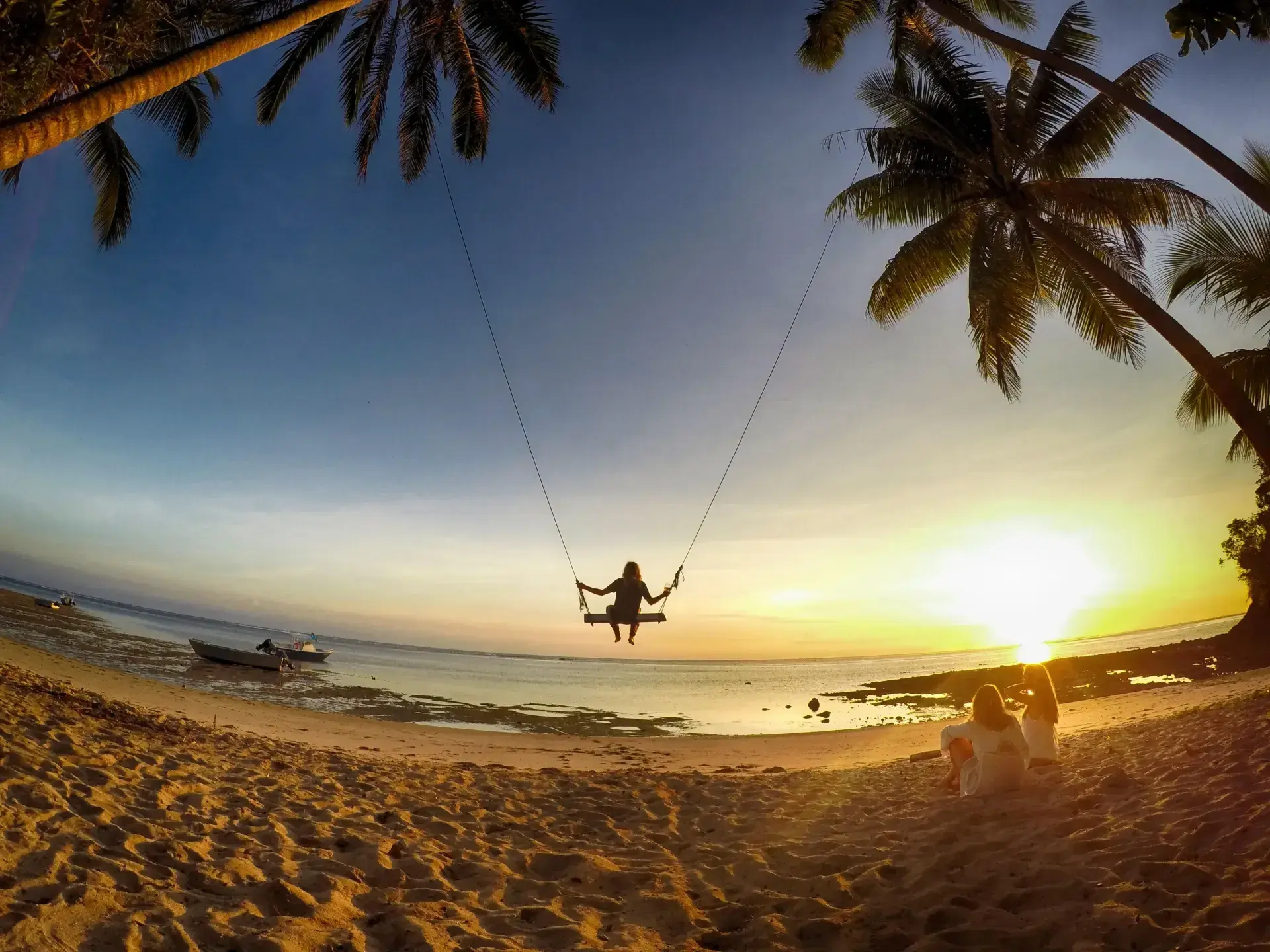 Beach swing at sunset with palm trees