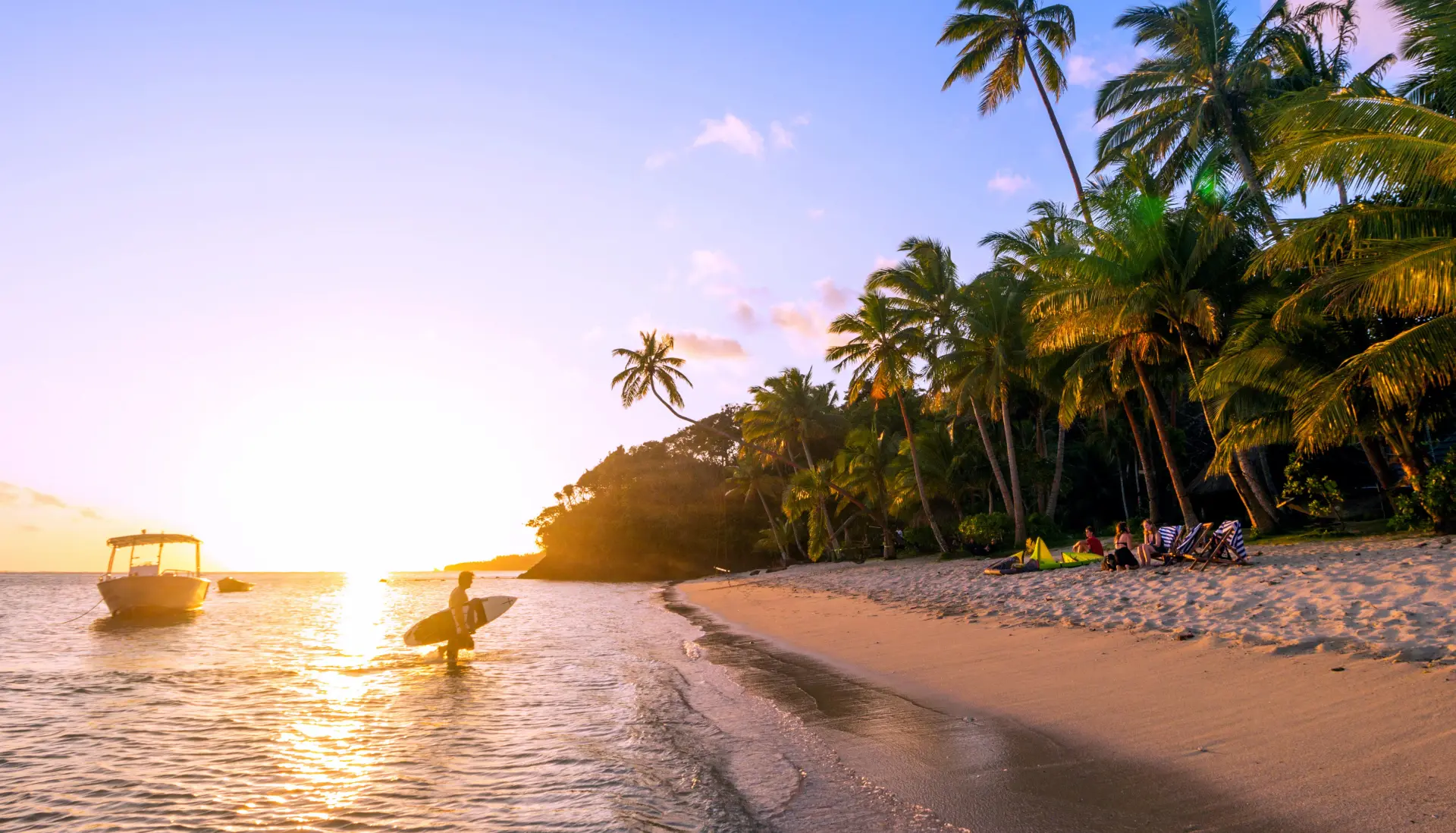 Sunset beach with surfer and palm trees